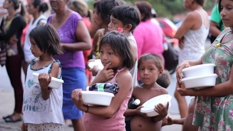 Venezuelans living in Simon Bolivar Square in Boa Vista line up for food provided by local community members.