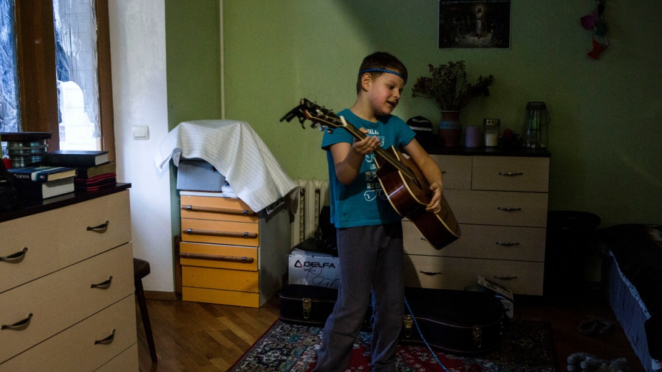 Igor fait semblant de faire de la musique avec la guitare de son père dans leur maison a Kiev