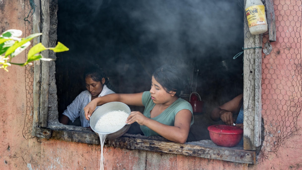 Aida Johana, 19 ans, cuisine le déjeuner pour sa famille chez Armando Pai. En tant que chef de la communauté, Armando est le seul résident à disposer d'une cuisine fonctionnelle. Aida et les 16 autres familles vivent dans des cabanes couvertes de sacs poubelle en plastique noir. 