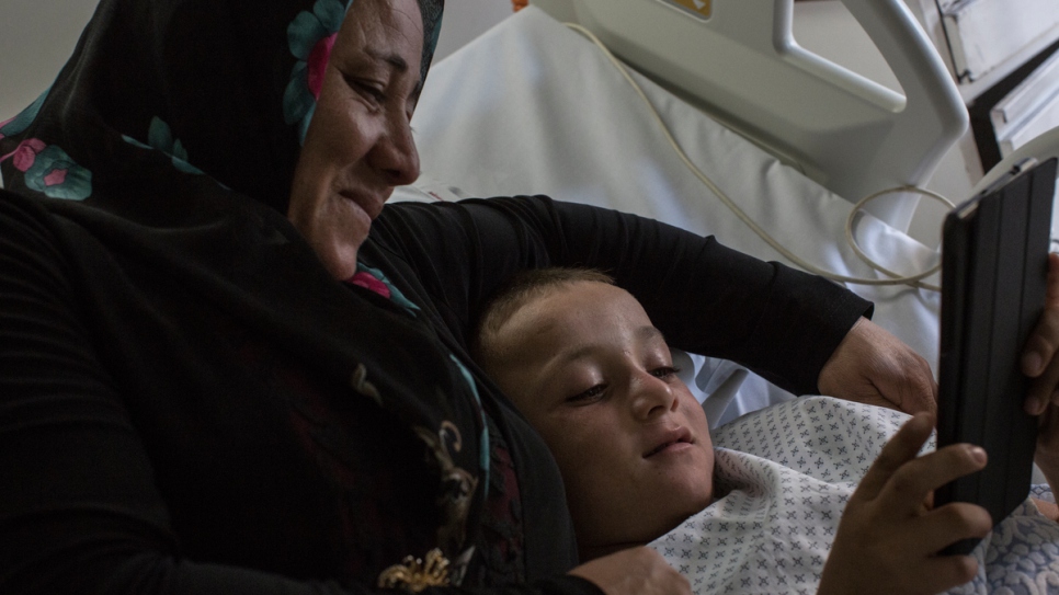 Issam et sa mère regardent un iPad avant l'intervention chirurgicale à l'hôpital du Sacré Coeur.  
