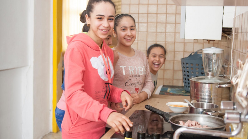 Les filles Al-Bashawat, Hadeel (à gauche) 15 ans, Fatima (partiellement cachée) 10 ans, Amneh (au centre) 13 ans, et Amal (à droite) 8 ans, en train de préparer le petit déjeuner dans leur logement de Vienne, après conclusion du processus de regroupement familial. 