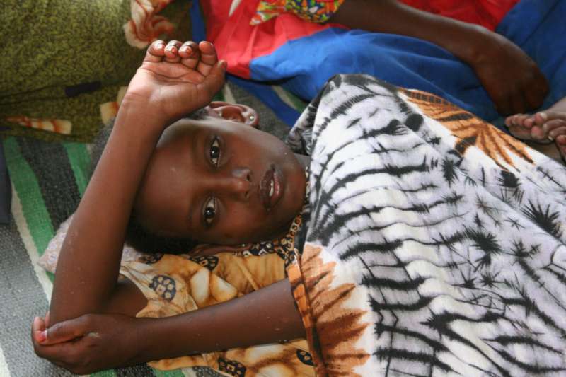 Cette jeune Somalienne tente de reprendre des forces, étendue sur le sol sous une grande tente. Elle a survécu à huit jours de dérive à bord d'un bateau d'un passeur.