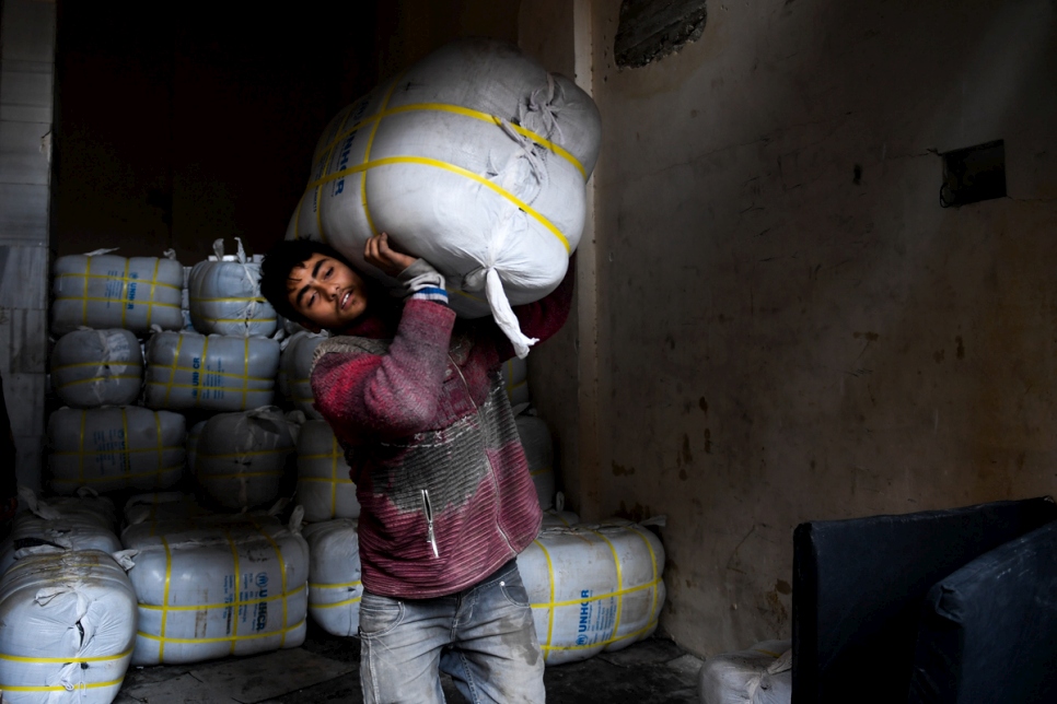 A volunteer distributes thermal blankets in Aleppo's Al-Mashatiyeh neighborhood.