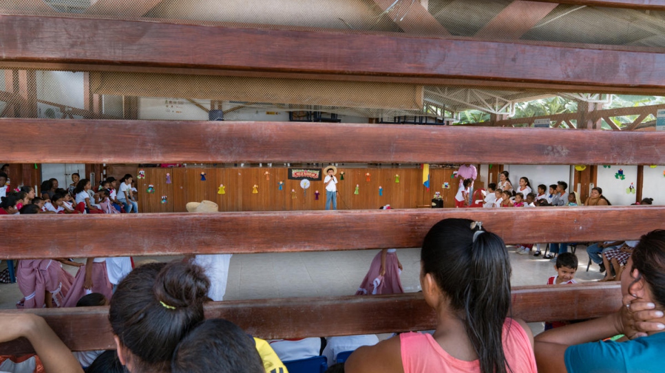 Children watch a student perform during a Christmas show at the school gymnasium in Nueva Esperanza. The events help give a sense of community to the children of displaced families.