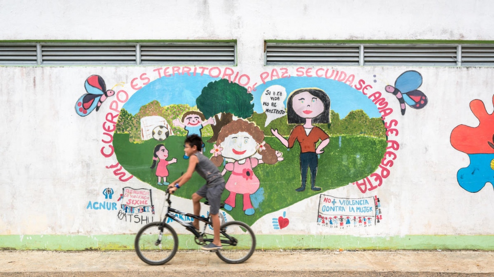 A child rides past a mural with a message of peace in the community of Nueva Esperanza, which is home to 228 families displaced by Colombia's armed conflict. 