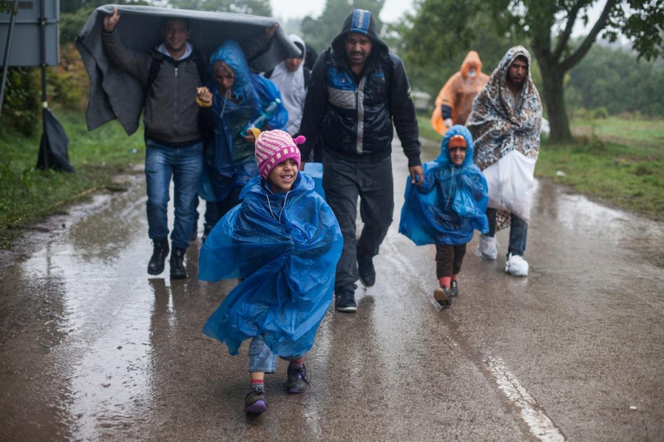 Refugees walk through the rain towards a bus that will transport them to Opatovac transit centre in Croatia.