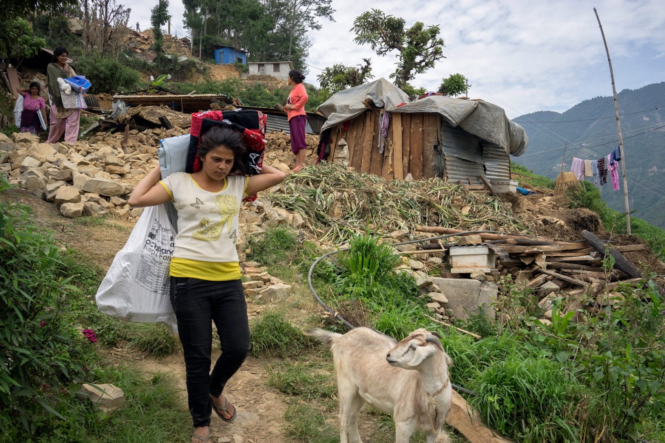 A young woman carries relief materials -- including a UNHCR plastic tarp and a hygiene kit -- in the hard-hit village of Jhankridanda, in Nepal's Lalitpur District.