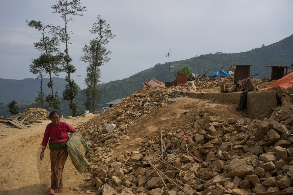 Shanti Lama, 54, the wife of Dan Bahadur Tamang, carries a mat salvaged from the rubble of her family's home in Jhankridanda village.