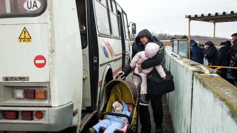 A man boards a bus with two children at Mariinka checkpoint.
