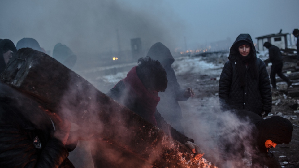 Refugees and migrants carry a railway sleeper behind the train station in Belgrade.