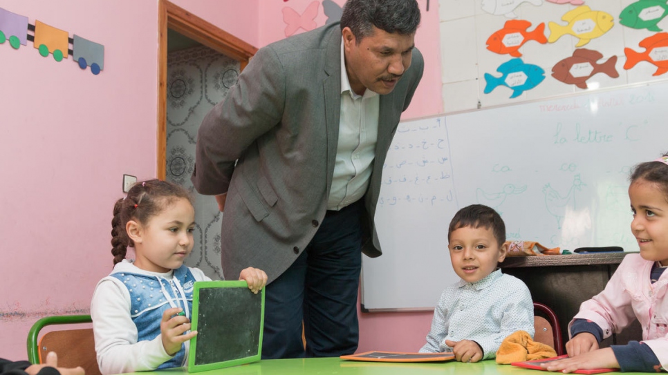 Yemeni refugee Abdullah teaches young students in a classroom in the school building