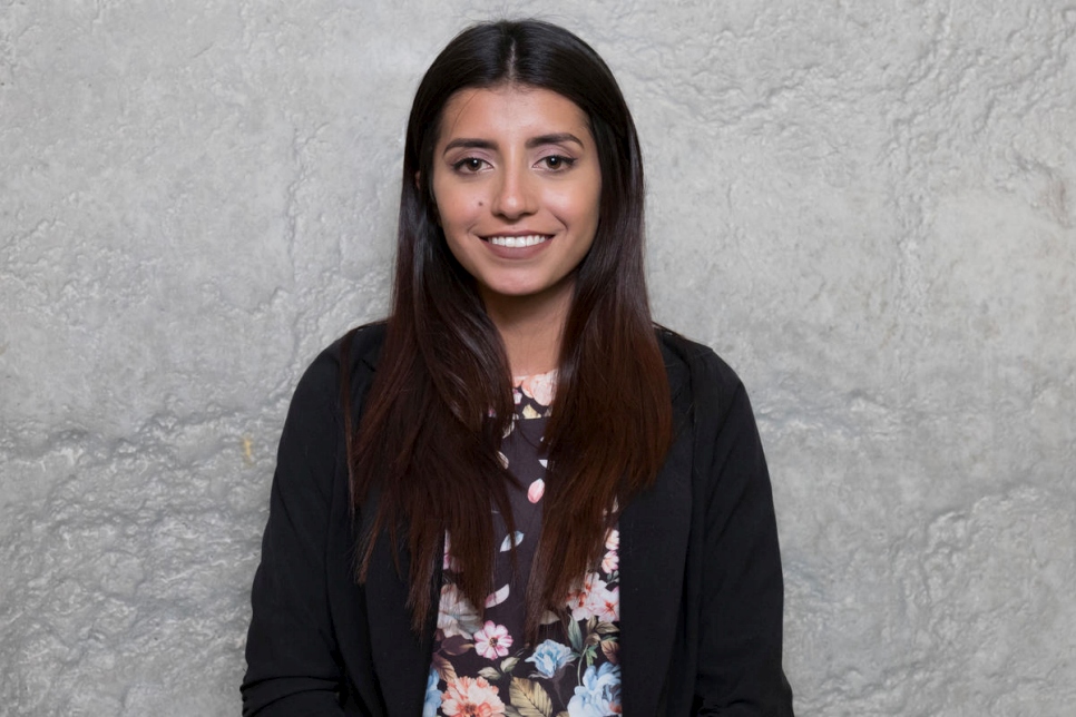 Portrait of a young woman standing against a grey background.