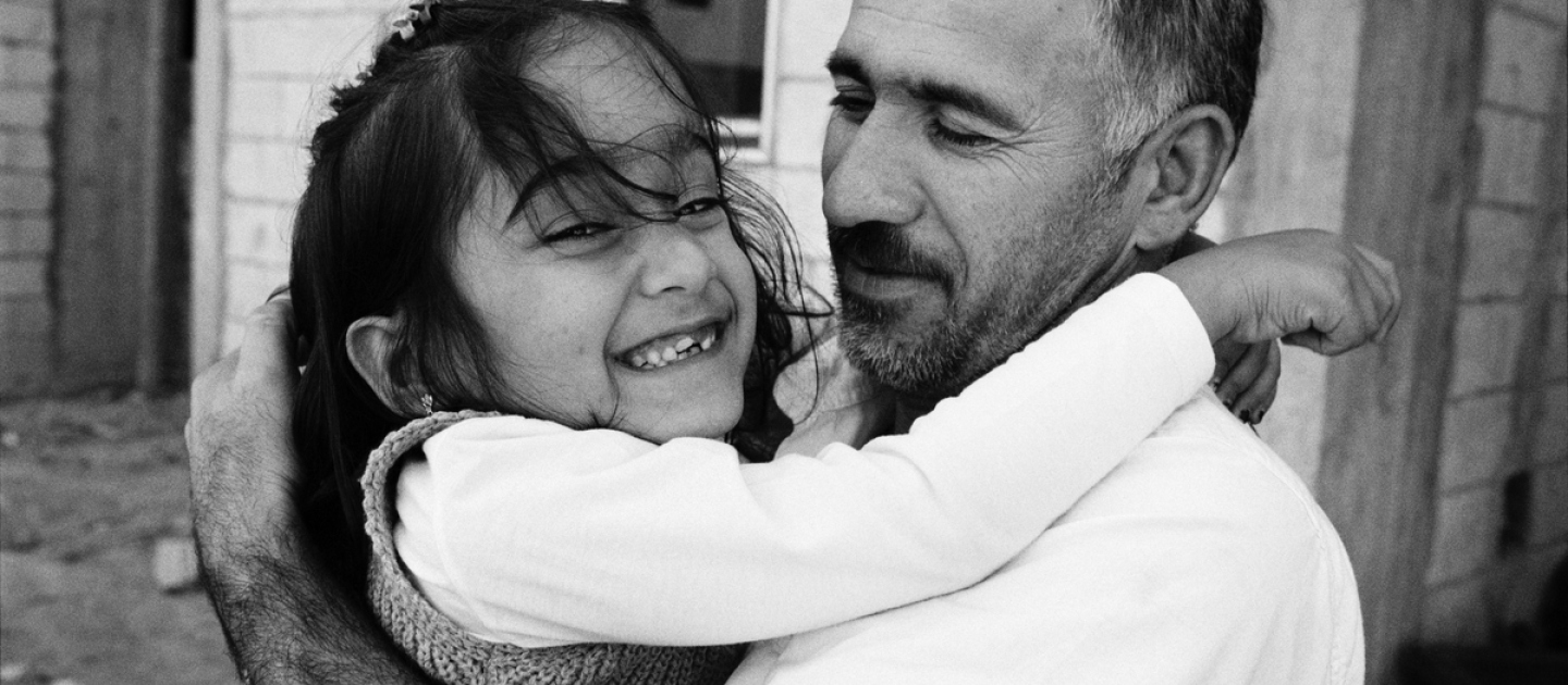 Aya hugs her father as they prepare to be resettled from Lebanon to France.