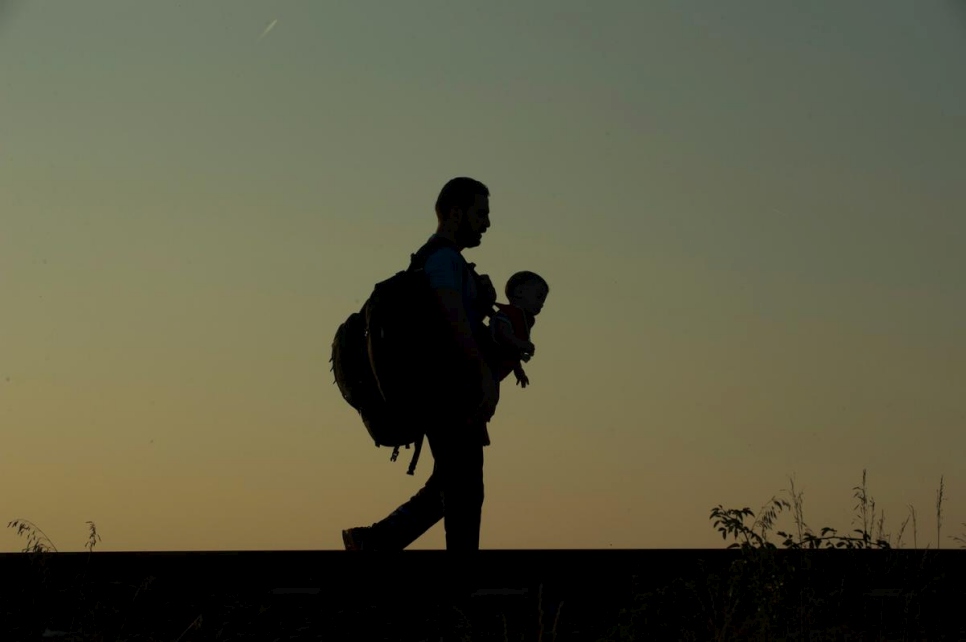 Hungary. Refugees father walking along rail tracks just after crossing the border