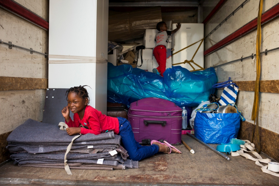 Amina et son frère Ibrahim, originaires de la RDC, aident à décharger le camion de déménagement devant leur nouvel appartement situé à Boussy-Saint-Antoine, au sud-est de Paris, après avoir été réinstallés avec leur mère Bora dans le cadre du dispositif du HCR en faveur des réfugiés vulnérables.
