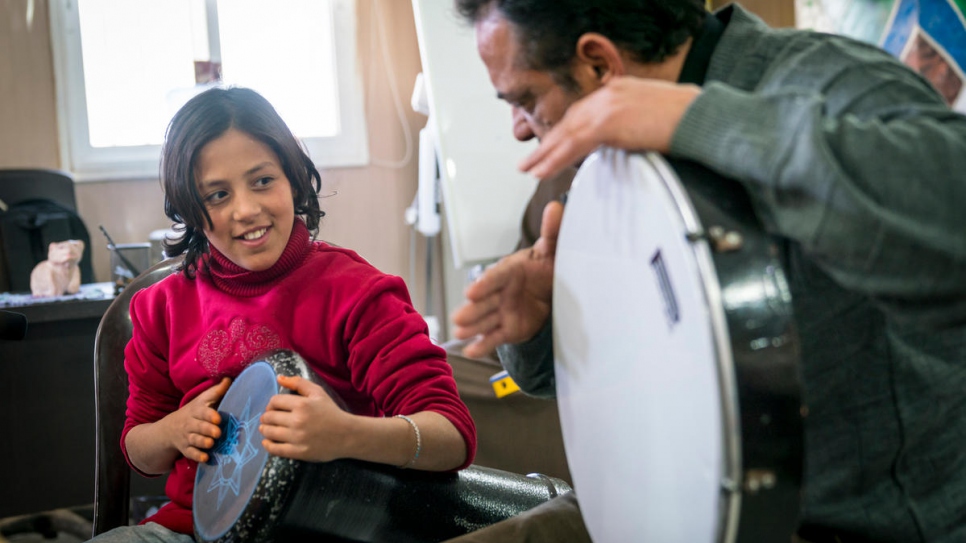 Syrian refugee Ehsan Al Khalili instructs 11-year-old Esraa Zallouf in a UNHCR-funded community centre in Azraq refugee camp, Jordan.