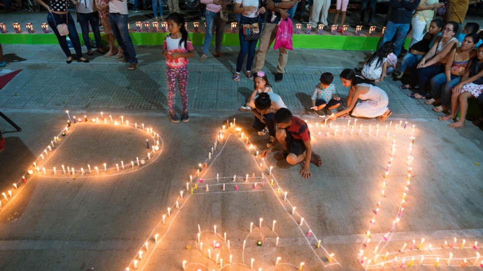 Women and children light candles forming the word "paz" ("peace") at a community event organized by the Life Weavers Women's Alliance in Mocoa, Colombia.