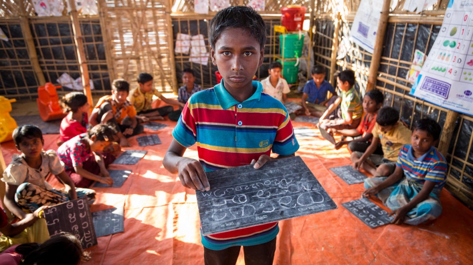 Ayatullah, 11, writes on a chalkboard in a classroom at Kutupalong Refugee Settlement. He recently fell ill with suspected diptheria and was successfully treated at a nearby medical centre.