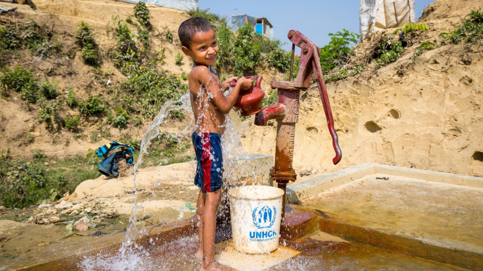 A young boy fills a bucket and kettle at a standpipe in Kutupalong refugee settlement.