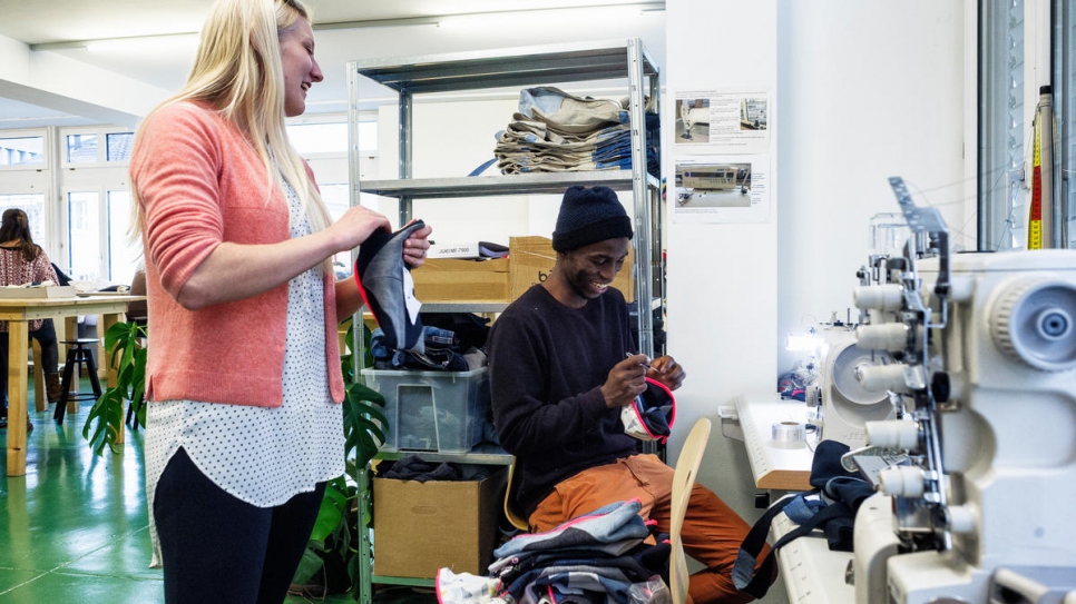 Cissé, a refugee from Côte d'Ivoire, works with staff member Helka. Cissé contributes to the design and creation of products developed by the organization.