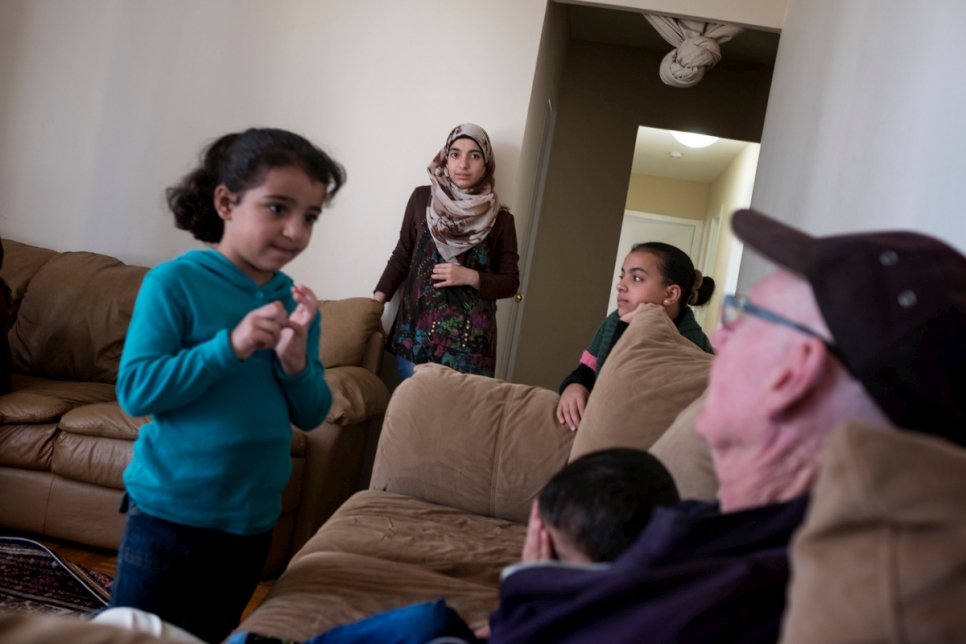 Le parrain Michael Adams (à droite) rend visite à la famille Nouman chez eux à Toronto. La famille Nouman fait partie des 13 000 réfugiés réinstallés au Canada au cours de la dernière année.