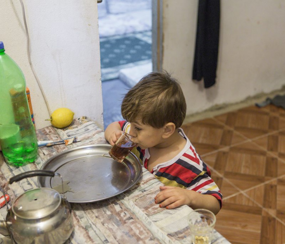 Omar drinks tea in the two-room apartment where his family has been living in Lebanon.