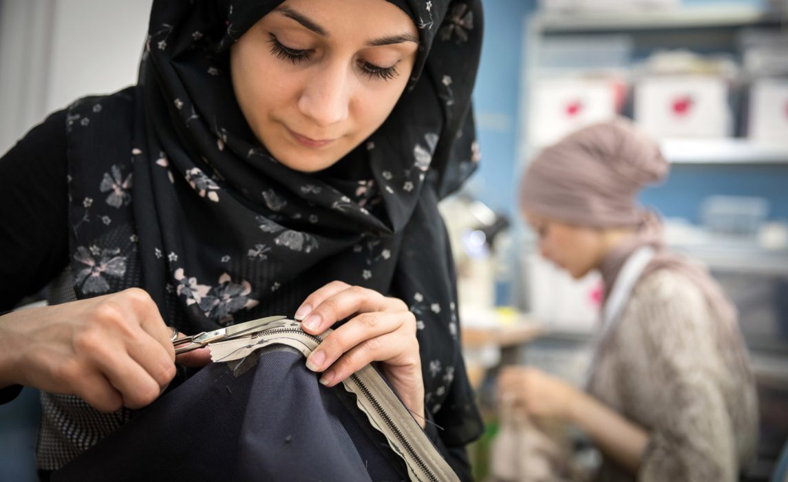 Esraa Ali, a 21-year-old refugee from Damascus, cuts a loose thread at fashion workshop in Frankfurt, Germany. ©UNHCR/Gordon Welters