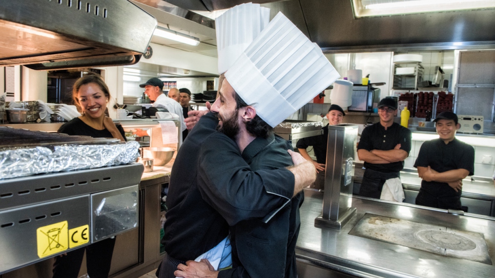 Syrian refugee Nadeem is presented with a chef's jacket with his name on it.