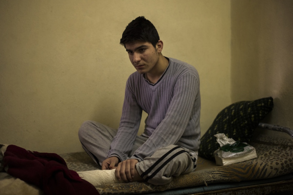 Asam sits on a thin mattress atop a metal bed frame as he recounts the day of his injury.