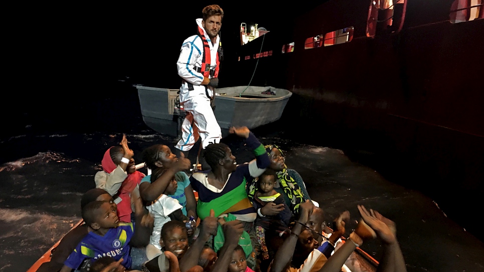 An Italian Coast Guard officer on a rescue boat during a night operation in the Mediterranean Sea.