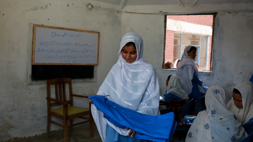 A young student admires her new uniform at Aqeela's school in Kot Chandana.