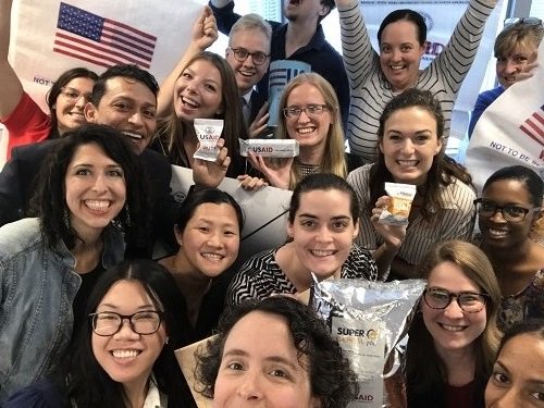 USAID Food for Peace staff pose with U.S. food aid products