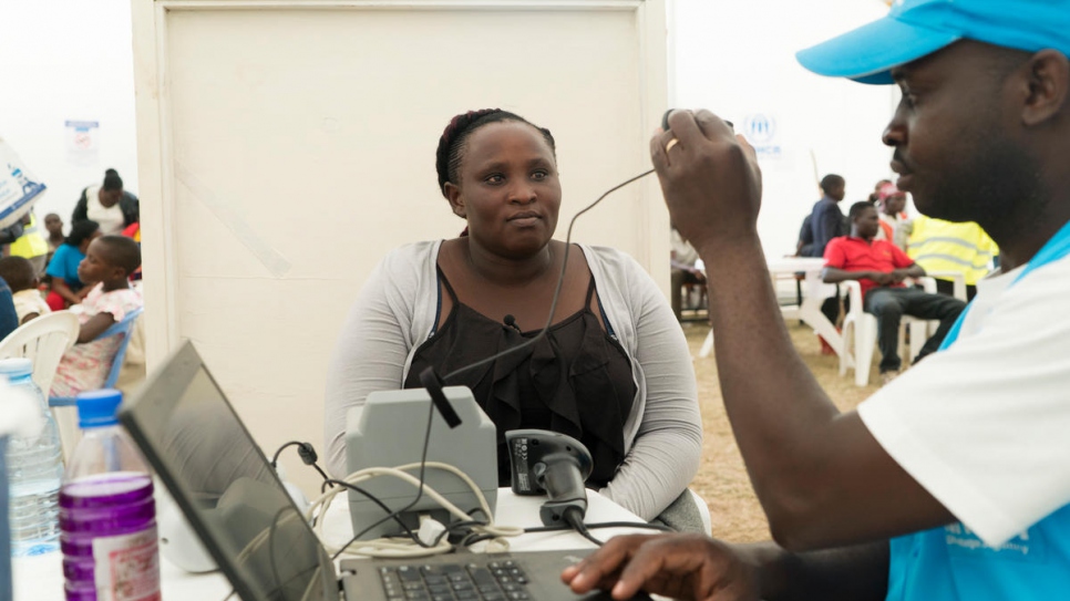 A UNHCR staff member helps to verify Jenipher and her daughter.