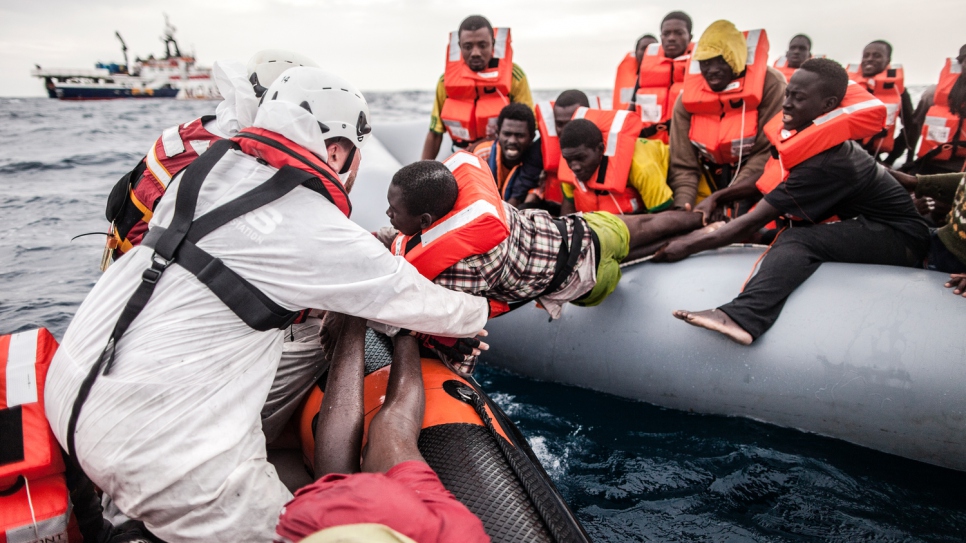 MOAS Search and Rescue Crew transfer people off a dinghy during a rescue operation in the  Mediterranean Sea.