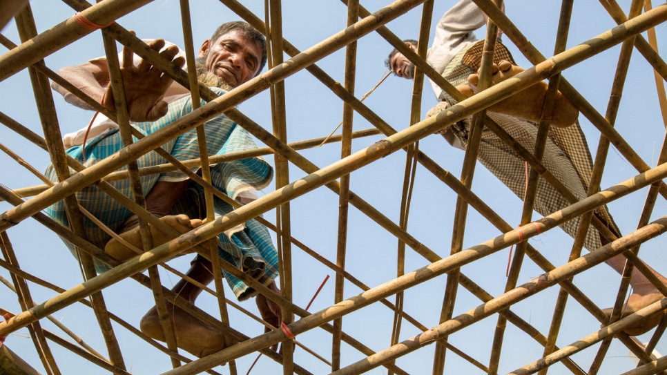 Mohammad Ishaq (à gauche) renforce le toit de son abri à l'aide de bambous fournis par le HCR aux réfugiés du camp de Kutupalong, au Bangladesh, en prévision de la mousson. 