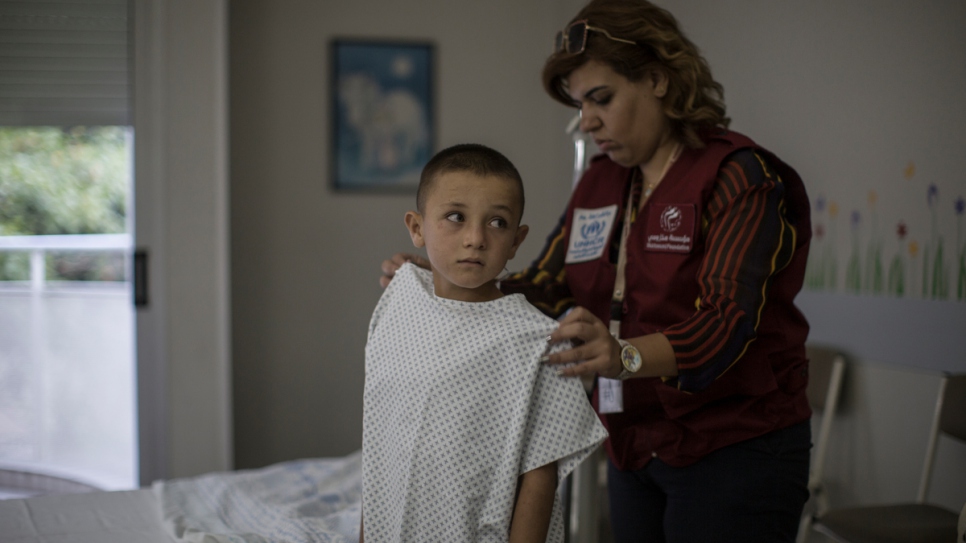 Issam is helped into a gown at the Sacre Coeur Hospital in Hazmieh ahead of cochlear implant surgery.