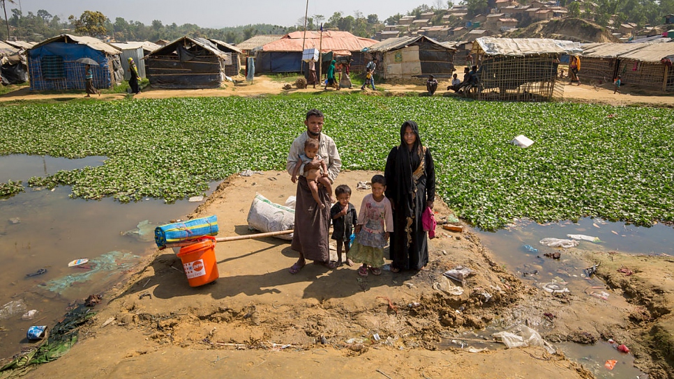 Mohammad Harez, son épouse Momena Begum et leurs enfants attendent sur une parcelle qui est menacée par les inondations dans le camp de Kutupalong, au Bangladesh. Ils doivent être transférés vers un abri sur un terrain plus élevé. 