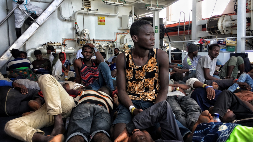 Réfugiés et migrants se reposent sur le pont du Dattilo, patrouilleur de la Garde côtière italienne. 