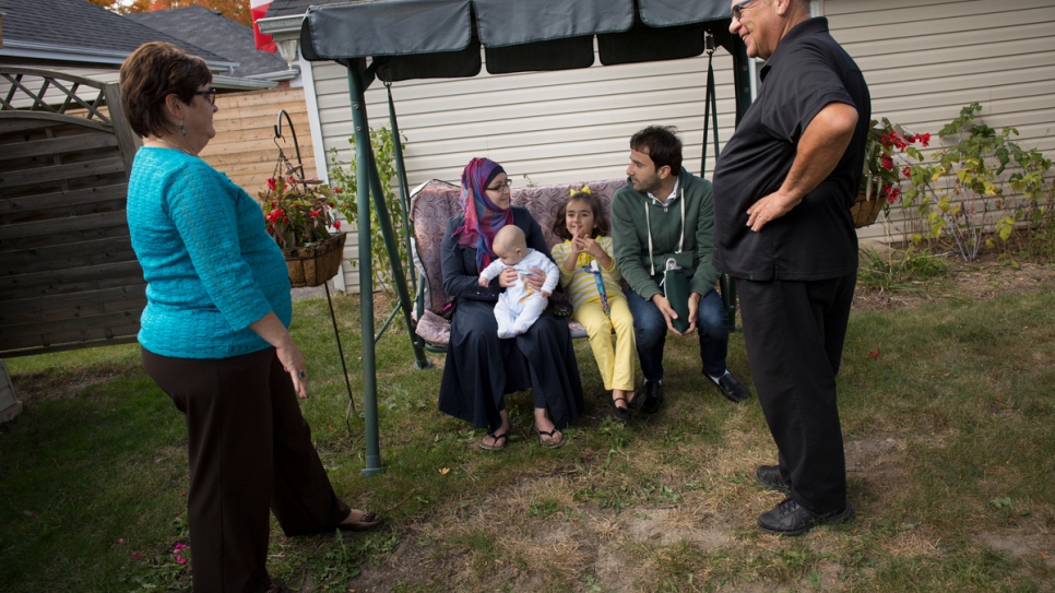 Les bénévoles Tanna et Joe sont assis avec Husam, Noura, Bayan et Adam, âgé de six mois, dans le jardin de leur maison à Peterborough. 