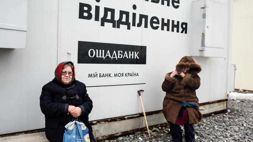 Nelia (left) has spent two hours waiting beside this mobile bank.