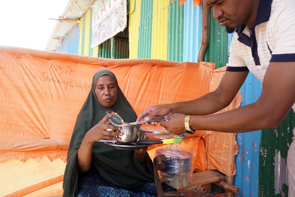 Fadumo Mohamed Ali receives a kitchen set from a shopkeeper in Sheder camp, Ethiopia. She is a beneficiary of the cash-based assistance project being piloted in the area. 