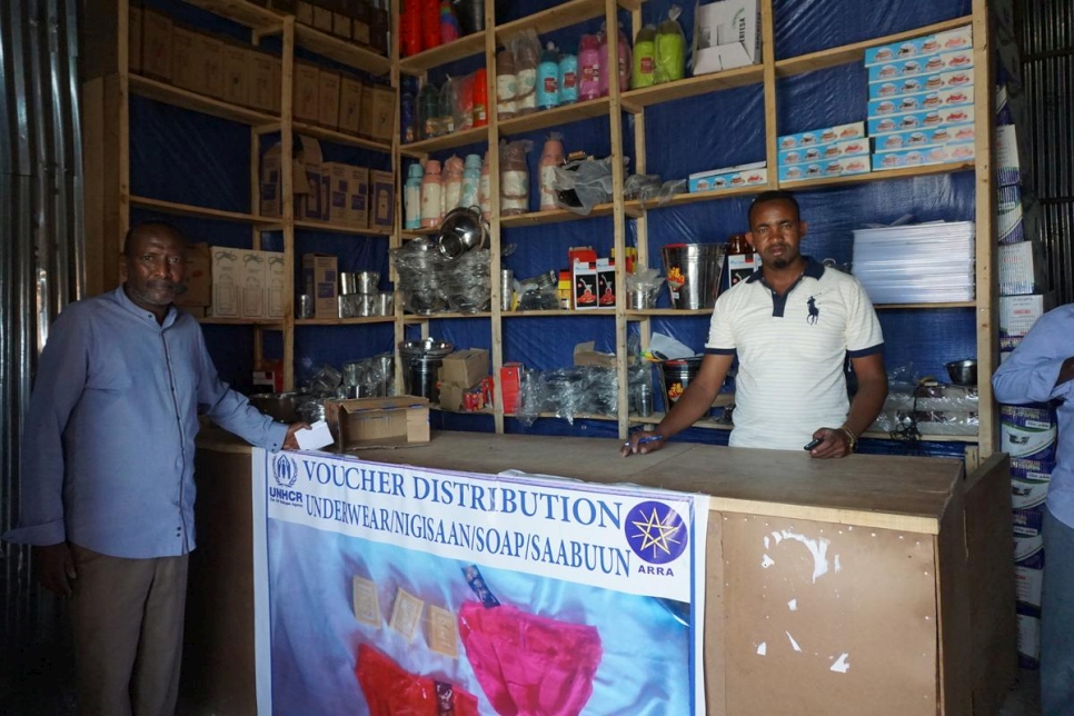Local shop owner Mohamed, from Sheder town, Ethiopia with one of his  refugee customers. He has seen an increase in business due to the cash assistance refugees receive.