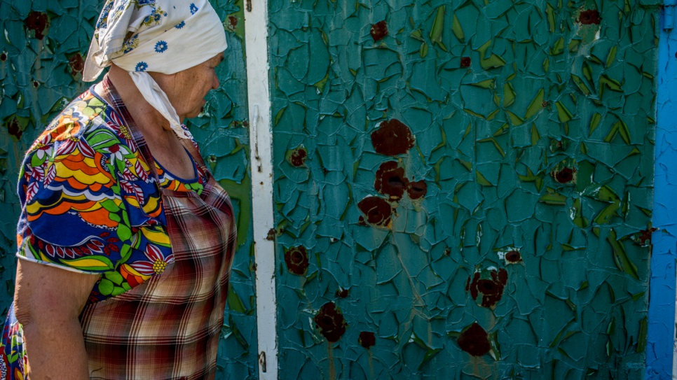 Shrapnel holes in an iron gate remind Ekaterina Belyavtseva of the conflict which raged near her home in eastern Ukraine during 2014.