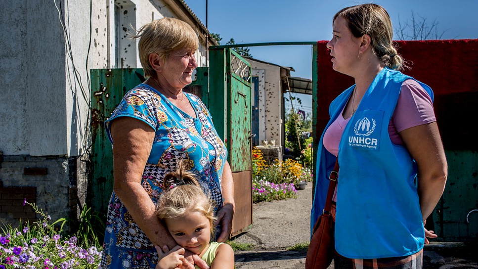 A UNHCR staff member talks to a local resident whose home was ruined in the 2014 fighting in the Luhansk region of eastern Ukraine.