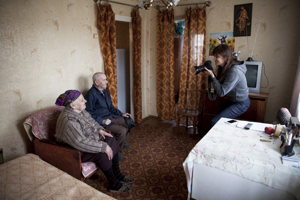 Helena en train de photographier Lina, 78 ans, et son mari Prokofiy, 86 ans, à Slovyansk, dans l'est de l'Ukraine. Leur maison a été bombardée en juin 2014, les forçant à déménager pour s'installer chez des parents. Ils ont finalement pu réintégrer leur foyer à la suite des travaux effectués par le HCR et ses partenaires.  