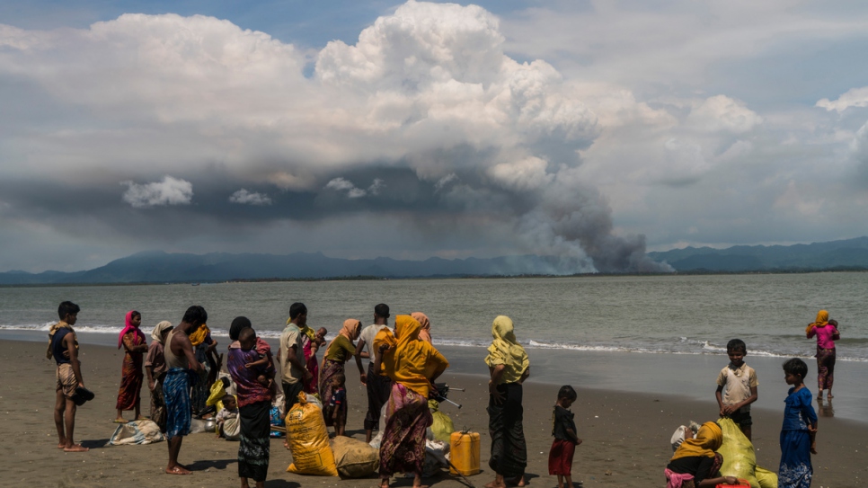Rohingya families gather on the beach at Dakhinpara, Bangladesh, after crossing the sea on fishing boats from Myanmar.