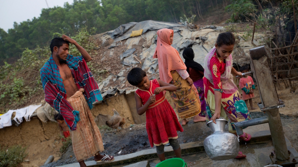 A recently arrived Rohingya family fill buckets with water from a well at a makeshift site in Cox's Bazar, Bangladesh, where tens of thousands of refugees have been living since an earlier outbreak of violence in Myanmar in October 2016.