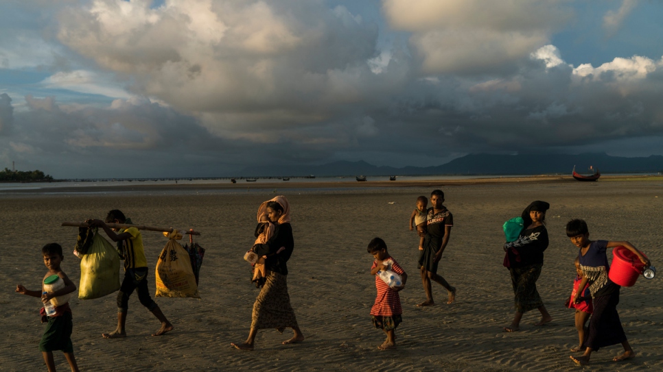 Rohingya families make their way across the beach at Dakhinpara, Bangladesh, after crossing the sea on fishing boats from Myanmar.