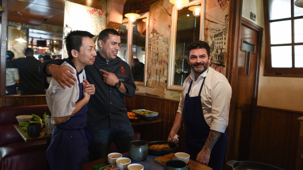 Le chef syrien réfugié, Mohammad Elkhaldy (au centre), s'apprête à cuisiner avec le chef français, Stephane Jego (à droite), au restaurant L'Ami Jean à Paris, le 16 juin 2017, à l'occasion du Refugee Food Festival. Mohammad est un célèbre chef et ancien animateur d'une émission culinaire à la télévision syrienne. 