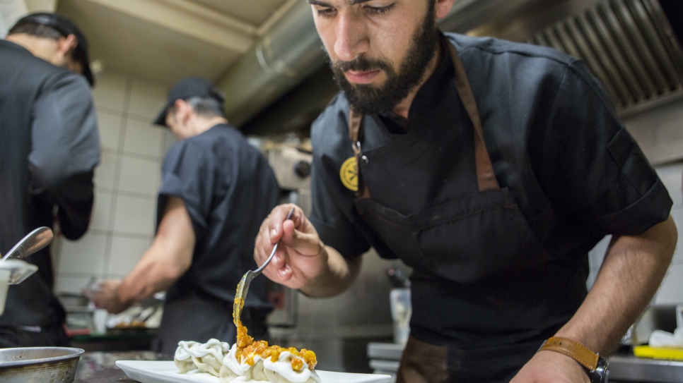 Le chef afghan réfugié, Reza Golami, cuisine au restaurant 'It' d'Athènes, en Grèce, le 22 juin 2017, à l'occasion du Refugee Food Festival. Cette année, le festival gastronomique se déroule dans 13 grandes villes européennes afin de changer le regard sur le statut de réfugié, offrir un tremplin aux chefs réfugiés en facilitant leur accès à l'emploi, et faire découvrir des cuisines venues d'ailleurs.